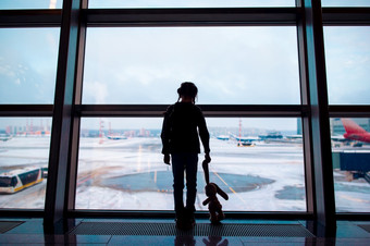 小女孩与她的兔子玩具机场附近大窗口而等待为登机小女孩机场附近大窗口而等待为登机