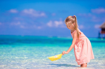 可爱的小女孩玩与折纸纸船绿松石海可爱的小女孩玩与折纸船绿松石海