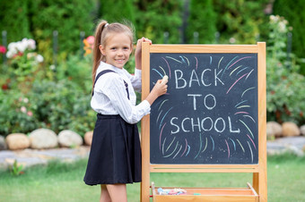 快乐小女学生写作的黑板回来学校在户外快乐小女学生与黑板户外