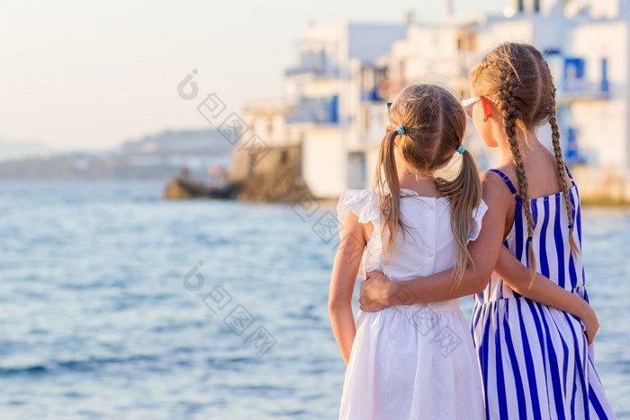 可爱的小女孩小威尼斯的大多数受欢迎的旅游区域米克诺斯岛希腊回来视图美丽的孩子们看小威尼斯背景可爱的小女孩小威尼斯的大多数受欢迎的旅游区域米克诺斯岛希腊