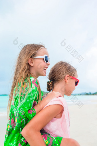 小女孩有有趣的热带海滩玩在一起浅水可爱的小姐妹海滩在夏天假期两个小快乐女孩有很多有趣的热带海滩玩在一起