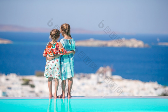 可爱的小女孩的边缘户外池他们的夏天假期希腊可爱的小姐妹海滩在夏天假期