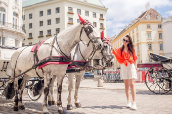 快乐女人走欧洲街年轻的有吸引力的旅游在户外维也纳城市的广场与两个马马车女人走城市年轻的有吸引力的旅游在户外意大利城市