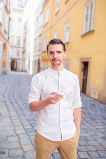 年轻的男人。与智能手机维也纳街男人。旅游与背包欧洲街高加索人男孩看与地图欧洲城市