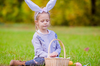可爱的女孩穿兔子耳朵持有篮子与复活节鸡蛋可爱的小女孩穿兔子耳朵与篮子完整的复活节鸡蛋春天一天在户外