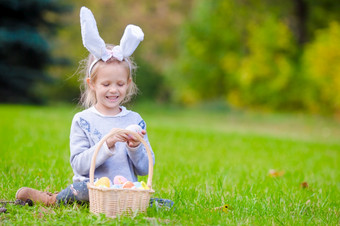 可爱的女孩穿兔子耳朵持有篮子与复活节鸡蛋肖像小孩子穿兔子耳朵与篮子完整的复活节鸡蛋春天一天在户外
