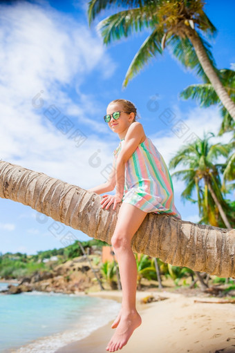 可爱的小女孩热带海滩坐着棕榈树在夏天假期可爱的小女孩坐着棕榈树在夏天假期白色海滩