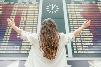 年轻的女人国际机场看的飞行信息董事会检查她的飞行年轻的女人国际机场看的飞行信息董事会检查为飞行