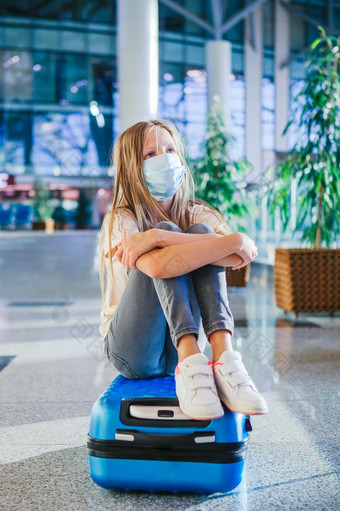 小可爱的孩子与外科手术面具脸保护国际机场保护对冠状病毒和抓手小孩子医疗面具机场等待为登机