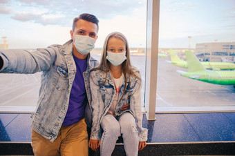家庭脸医疗面具机场父亲和孩子穿口罩在冠状病毒和流感爆发保护对冠状病毒和抓手爸爸和小女孩与医疗面具机场保护对冠状病毒和抓手