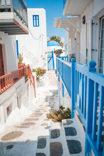 美丽的体系结构建筑外与基克拉迪群岛的风格希腊的狭窄的街道的岛与蓝色的阳台楼梯和花希腊