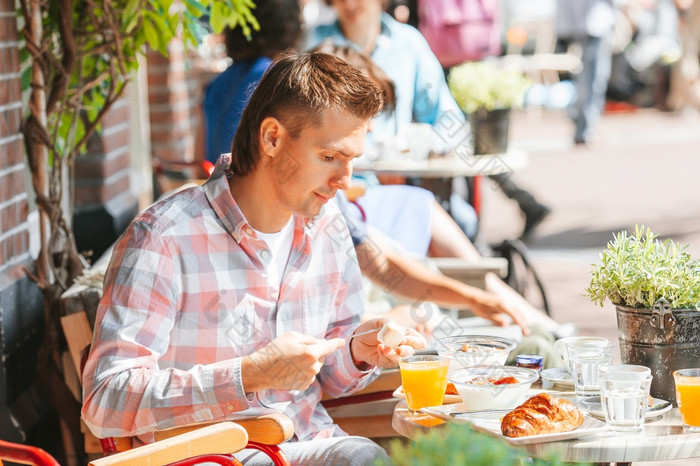 年轻的男人。有早餐户外咖啡馆男人。有breakfastin户外restaraunt