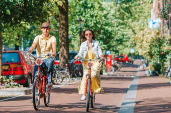年轻的快乐ouple自行车老街道阿姆斯特丹年轻的快乐高加索人夫妇自行车老街道阿姆斯特丹