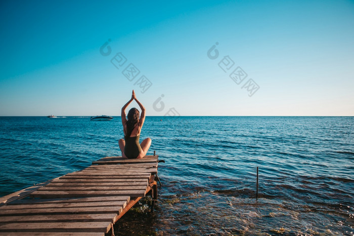 年轻的美丽的女人女人练习瑜伽的码头年轻的美丽的女人瑜伽的海滩
