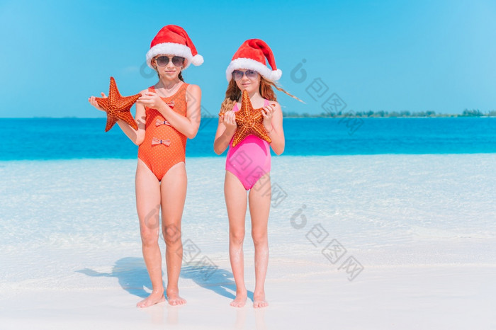 可爱的小女孩圣诞老人帽子与海星白色空海滩可爱的小女孩与海星白色空海滩