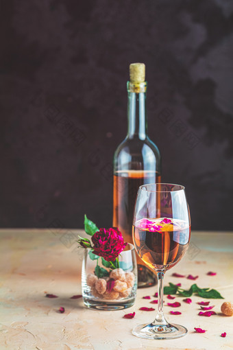 瓶玫瑰酒和玻璃服务与玫瑰酒和玫瑰花瓣玫瑰和蜜饯水果玻璃粉红色的混凝土表格和黑暗背景美丽的情人节婚礼问候卡