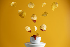 美味的土豆芯片下降成打击与番茄酱汁冻的空气黄色的食物艺术背景