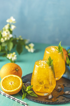 橙色喝与冰两个玻璃橙色冰喝与新鲜的薄荷木绿松石表格表面含酒精的不含酒精的喝饮料