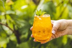 女人手持有橙色喝与冰夏天阳光明媚的花园背景新鲜的鸡尾酒饮料与冰水果和草装饰