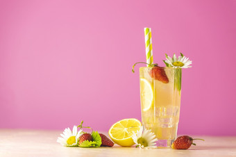 眼镜冷冰冷的让人耳目一新喝与柠檬和草莓明亮的粉红色的背景新鲜的鸡尾酒饮料与<strong>冰水</strong>果草和洋甘菊装饰
