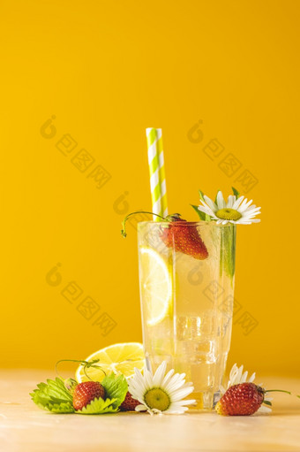眼镜冷冰冷的让人耳目一新喝与柠檬和草莓明亮的黄色的背景新鲜的鸡尾酒饮料与<strong>冰水</strong>果草和洋甘菊装饰