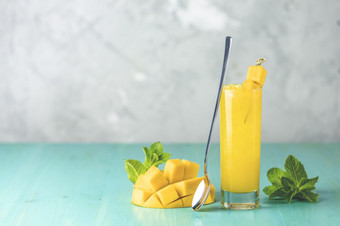 让人耳目一新夏天鸡尾酒使芒果冷喝喝与冰蓝色的灰色的背景新鲜的夏天冰冷芒果鸡尾酒汁与薄荷和芒果水果
