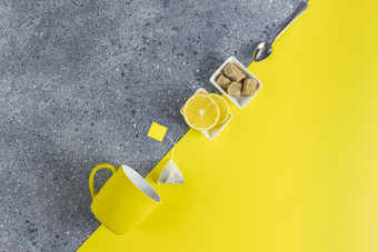 有创意的茶食物背景最终灰色的和照明趋势颜色茶柠檬杯和勺子灰色的和黄色的表格表面前视图