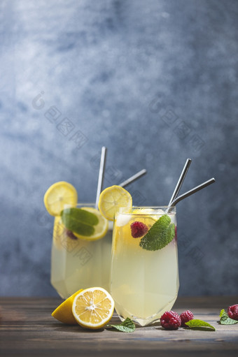 两个眼镜冷冰冷的让人耳目一新喝与柠檬和树莓服务黑暗木表格表面新鲜的鸡尾酒饮料与冰水果和草装饰