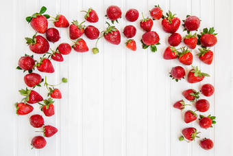 成熟的红色的草莓分散白色木表格背景与草莓的地方为文本成熟的红色的草莓分散白色木表格背景与草莓