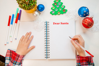 亲爱的圣诞老人信圣诞节卡孩子持有笔写白色表木背景与新一年rsquo装饰童年梦想关于礼物新一年概念亲爱的圣诞老人信圣诞节卡孩子持有笔写白色表木背景与新一年rsquo装饰