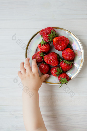 手孩子与草莓乡村背景板草莓的概念夏天健康的吃视图从以上公寓手孩子与草莓乡村背景板草莓