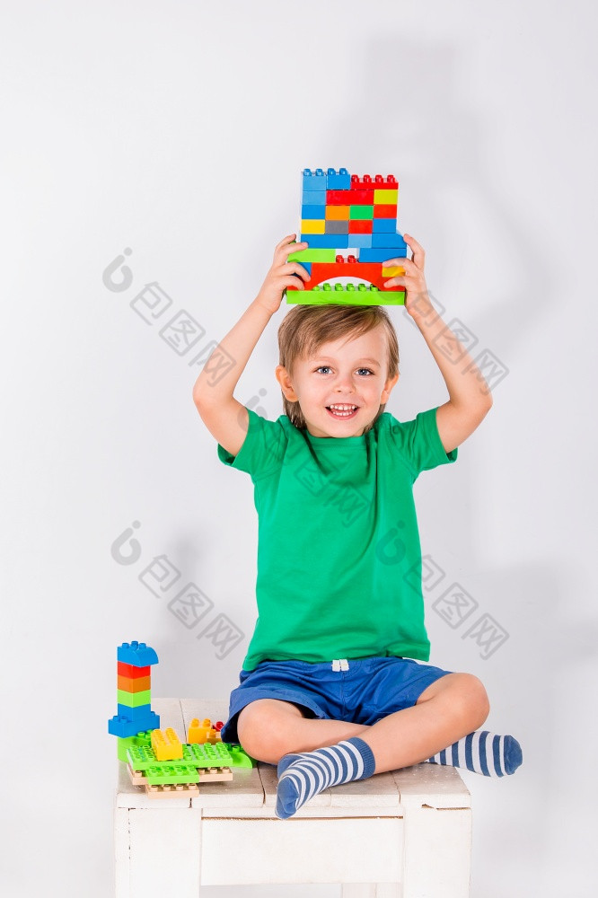 小男孩玩与很多色彩斑斓的塑料块构造函数室内小男孩玩与很多色彩斑斓的塑料块构造函数
