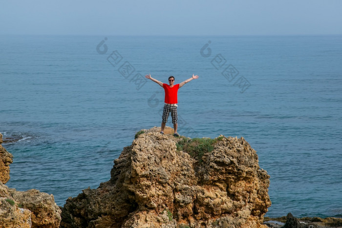完整的长度肖像年轻的男人。看海波从岩石海岸克里特岛希腊完整的长度肖像年轻的男人。看海波克里特岛希腊