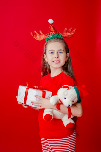 肖像有趣的快乐的女孩与绷带角她的头拥抱<strong>泰迪熊</strong>圣诞节睡衣孤立的明亮的红色的背景的孩子点手的地方为文本肖像有趣的快乐的女孩与绷带角她的头拥抱<strong>泰迪熊</strong>圣诞节睡衣孤立的明亮的红色的背景