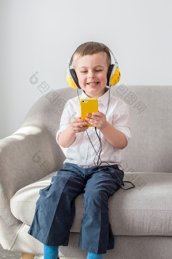 男孩听音乐与耳机坐着的沙发上男孩听音乐