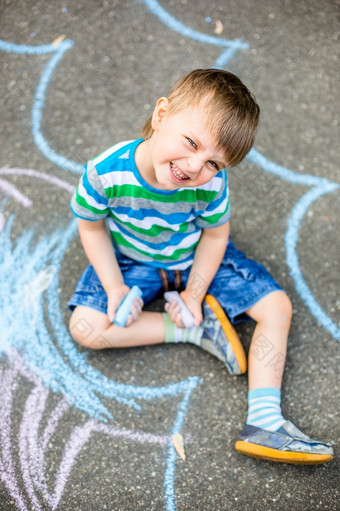 可爱的男孩和女孩画与粉笔的人行道上的公园夏天活动为孩子们有创意的画孩子与蓝色的粉笔的路可爱的男孩和女孩画与粉笔的人行道上的公园