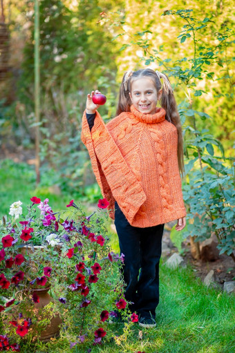 可爱的快乐女孩与苹果他的手的花园阳光明媚的秋天一天秋天肖像在户外可爱的快乐女孩与苹果他的手的花园阳光明媚的秋天一天