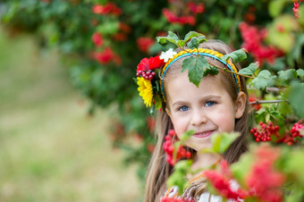 小女孩与金发碧眼的头发乌克兰人服装站附近布什荚莲属的植物小女孩与金发碧眼的头发乌克兰人服装站附近