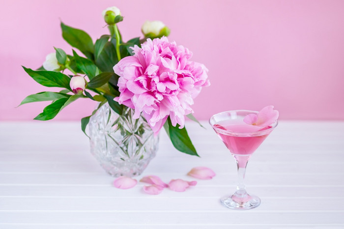 粉红色的牡丹下一个玻璃粉红色的酒粉红色的背景粉红色的牡丹下一个玻璃粉红色的酒