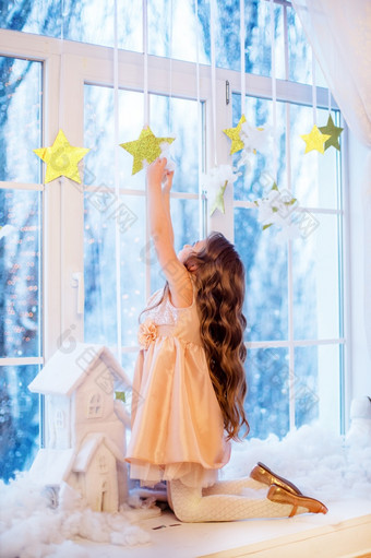 可爱的小女孩与卷曲的头发的窗口期待圣诞节和新一年rsquo魔法有趣的情绪冬天一天可爱的小女孩与卷曲的头发的窗口期待圣诞节和新一年rsquo魔法