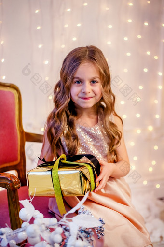 可爱的小女孩与卷曲的头发与礼物圣诞节夏娃之前的新一年快乐的情绪期待惊喜可爱的小女孩与卷曲的头发与礼物圣诞节夏娃之前的新一年