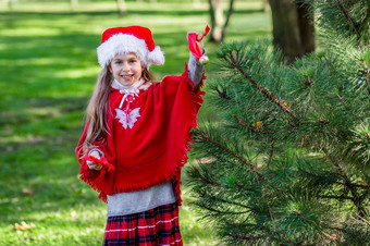 可爱的女孩<strong>装修</strong>的圣诞节树在户外的院子里之前的假期快乐圣诞节和快乐假期可爱的女孩<strong>装修</strong>的圣诞节树在户外的院子里之前的假期
