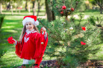 可爱的女孩装修的圣诞节树在<strong>户外</strong>的院子里之前的假期快乐圣诞节和快乐假期可爱的女孩装修的圣诞节树在<strong>户外</strong>的院子里之前的假期