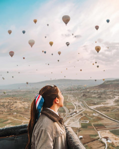 亚洲女人看色彩斑斓的热空气气球飞行在的谷卡帕多西亚火鸡这浪漫的时间