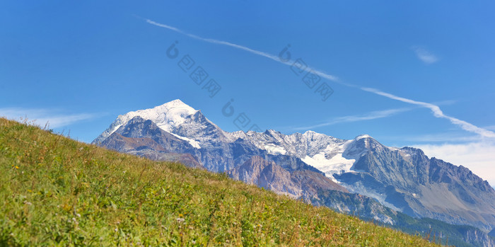 峰会高山山覆盖与雪回来绿色草地下蓝色的天空覆盖与雪回来绿色草地下蓝色的天空