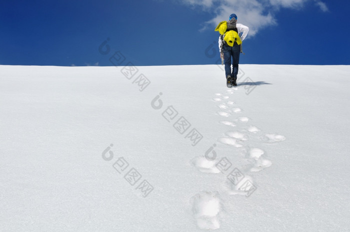 徒步旅行者攀爬雪山下蓝色的天空