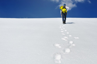 徒步旅行者攀爬雪山下蓝色的天空