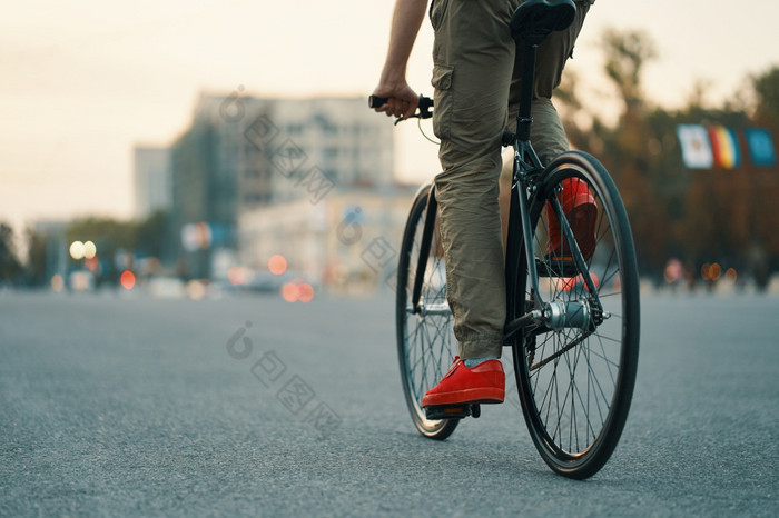 特写镜头休闲男人。腿骑经典自行车城市灰色的路穿红色的运动鞋和舒服的裤子复制空间特写镜头休闲男人。腿骑经典自行车城市路