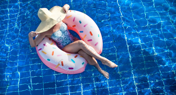 的女人的他放松充气圆的形式甜甜圈的蓝色的池的视图从的前的概念夏天消遣女人他放松充气圆的池
