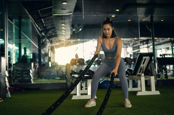 女人与战斗绳子战斗绳子锻炼的健身健身房练习概念健康的概念重锻炼健身房健身